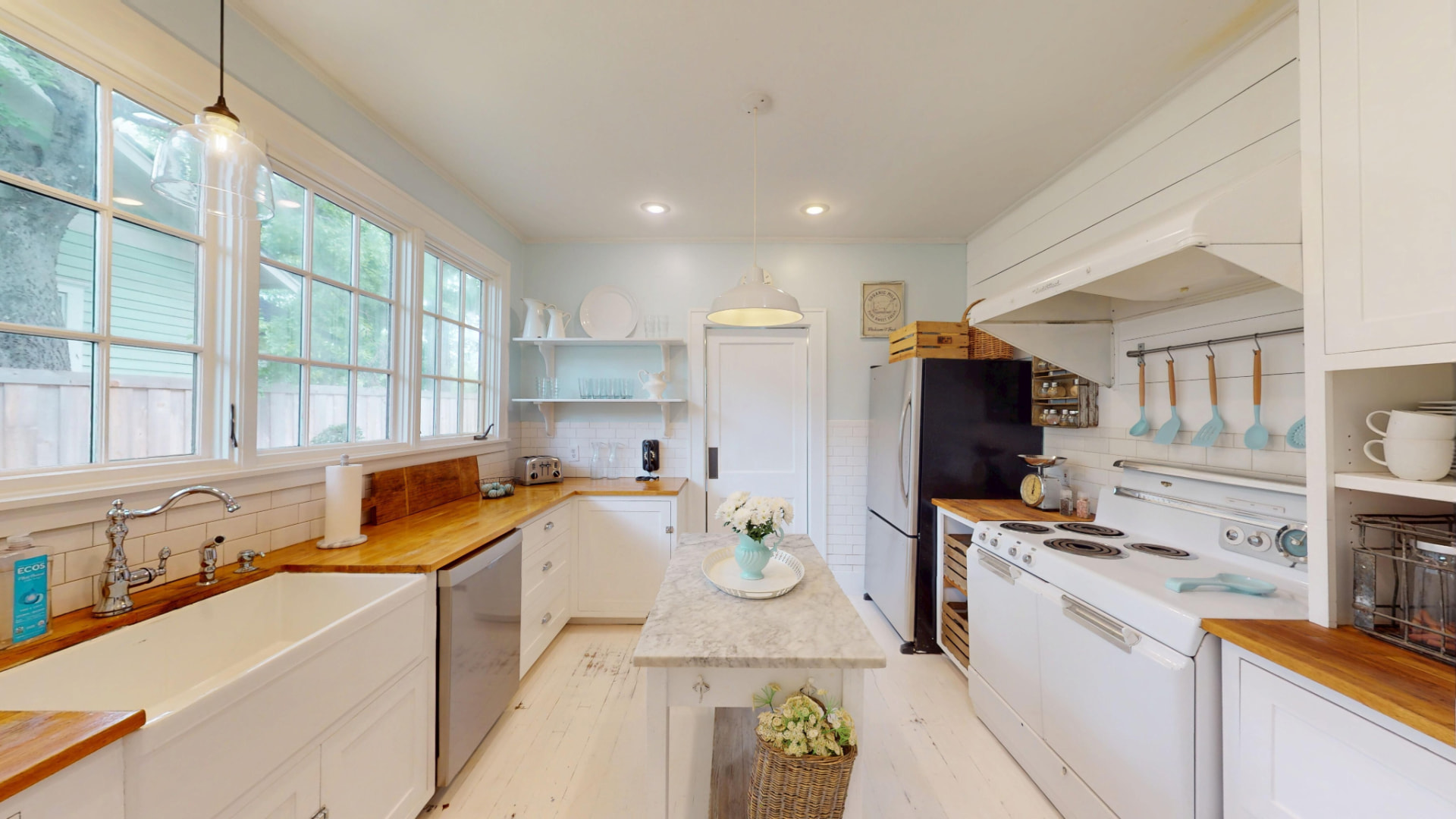 Renovated kitchen with custom white cabinetry, butcher-block counters, marble island, subway tile, and a vintage white stove