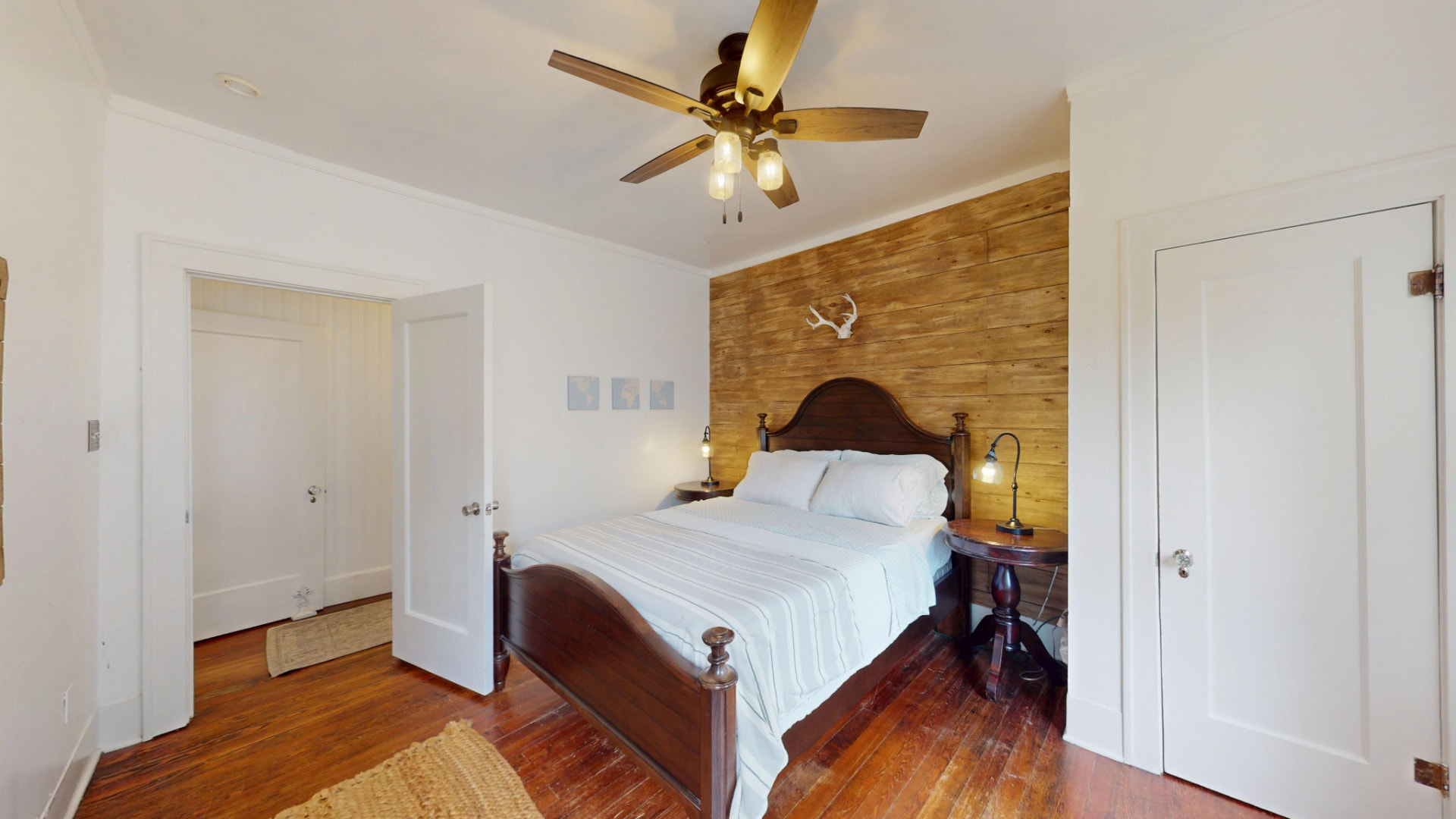 Bedroom with reclaimed-wood accent wall, ceiling fan, and dark wood four-poster bed