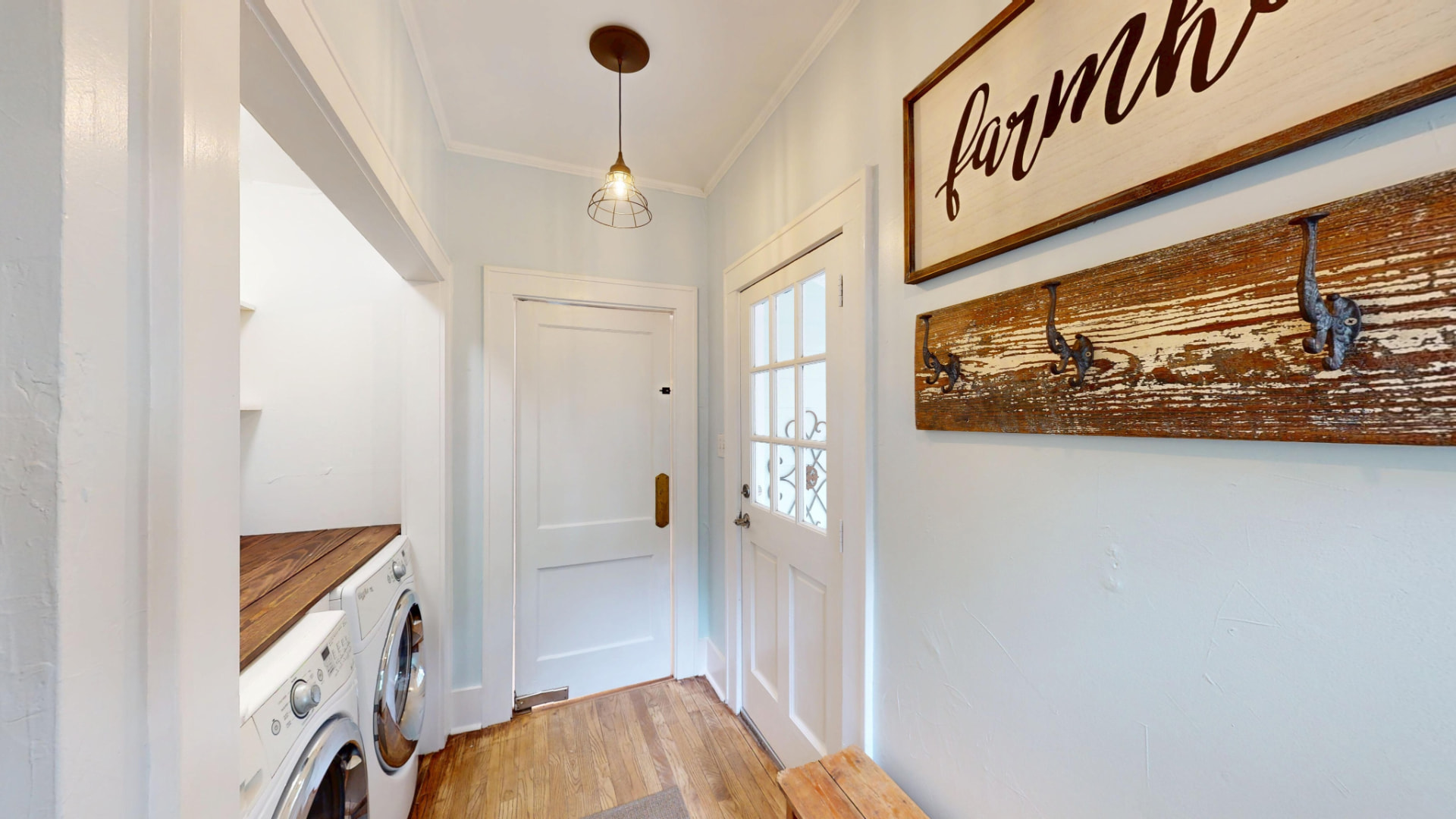 Mudroom off the back entry with stacked washer and dryer, reclaimed-wood coat rack, and a caged pendant light
