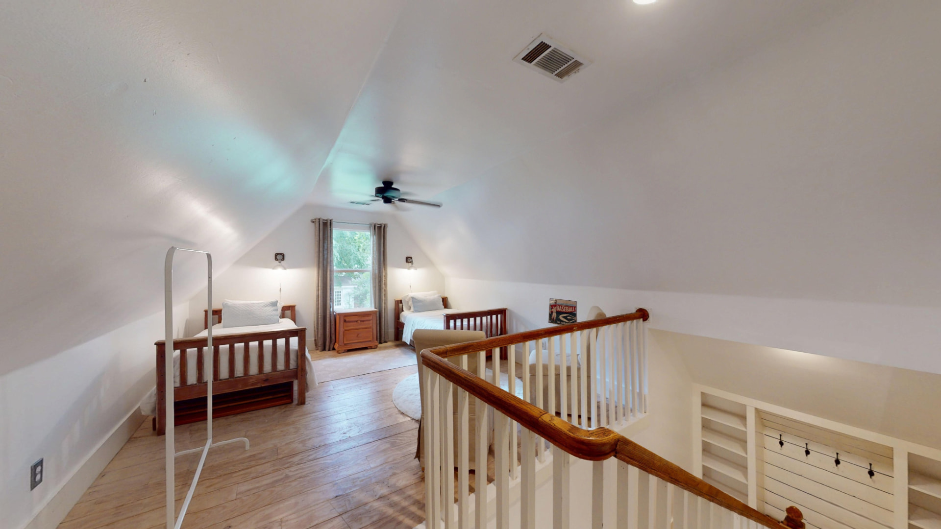 Upstairs loft bedroom with vaulted ceiling, twin beds, hardwood floors, and a dormer window
