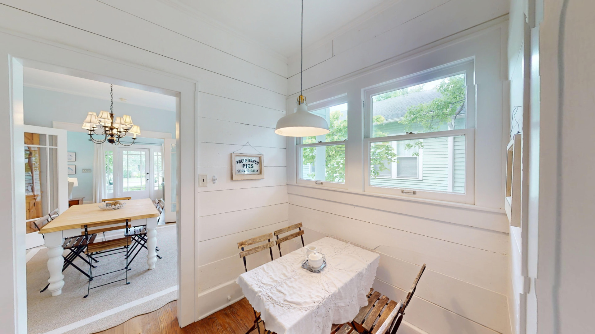 Sunny breakfast nook off the kitchen with shiplap walls and windows looking onto the side yard