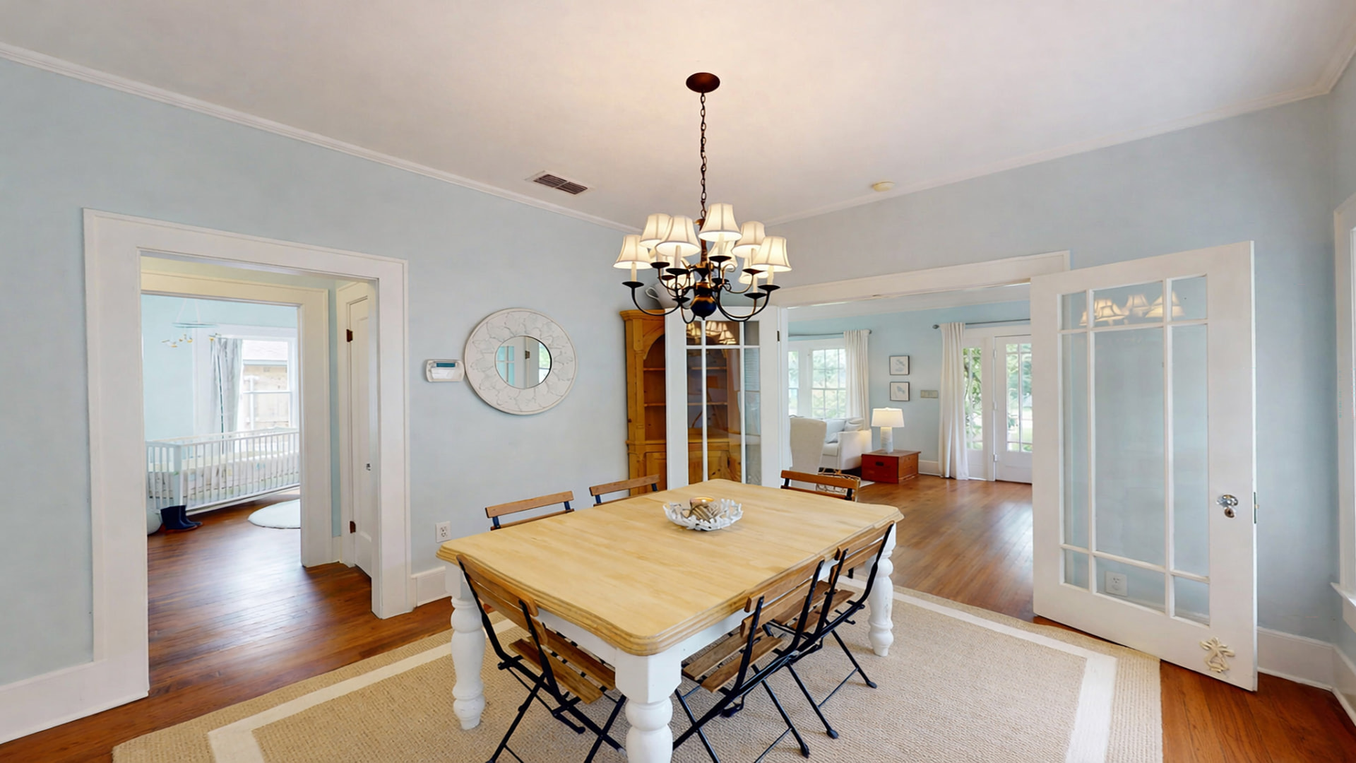 Dining room with farmhouse table, chandelier, French doors, and a view through to the living room
